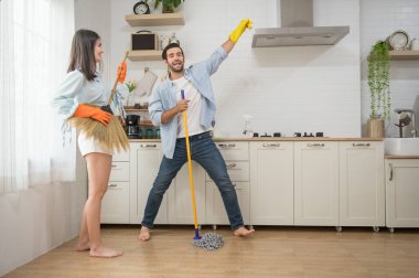 Mutlu çift mutfak temizliği yaparken eğleniyor dans etmek için müzik aletleri yerine süpürge ve paspas kullanıyorlar.