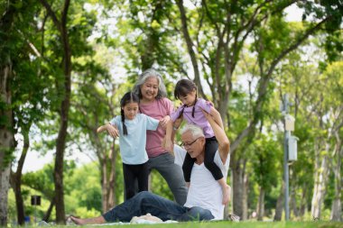 Mutlu Asyalı aile çocukları parkta büyükannesi ve büyükbabasıyla oynuyor, yaz tatili konsepti.