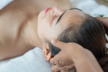 Genç Asyalı kadın masaj yaptırıyor, kaplıcada keyif alıyor ve dinleniyor.