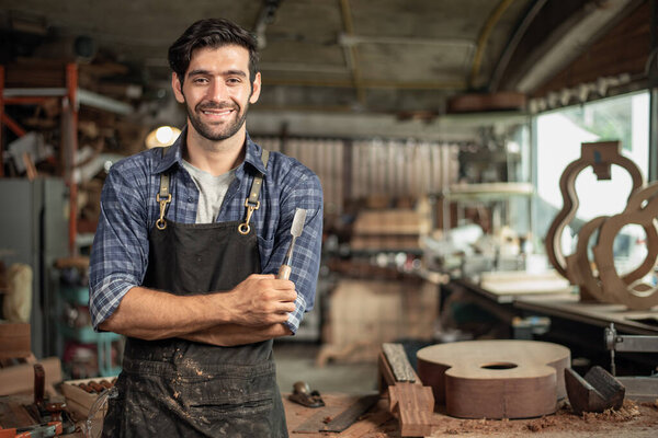 Portrait of guitar luthier small business owner in workroom, arts and craft concept