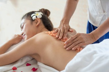 Genç Asyalı kadın spa salonundan zevk alıyor güzellik terapisti sağlık merkezindeki kadına tuz banyosu yaptırıyor, temizlik ve cilt bakımı konsepti uyguluyor.