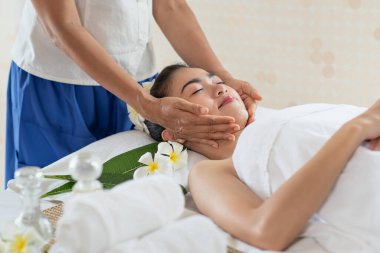 Genç Asyalı kadın spa salonunda masaj yaptırıyor, keyif alıyor ve rahatlatıyor, sağlıklı bir konsept.