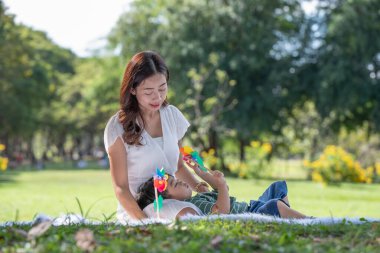 Mutlu Asyalı aile bahçede annesiyle yel değirmeni oynarken eğleniyor.