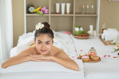 Genç Asyalı kadın masaj yatağında uzanıyor, spa salonunda dinleniyor.