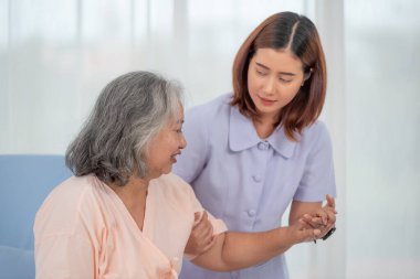 Klinikte ya da hastanede yaşlı bir kadının elini tutan gülümseyen Asyalı doktor, yaşlıların sağlık hizmetleri kavramı