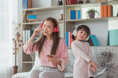 Mutlu Asyalı çocuk annesiyle bir odada eğleniyor ve dans ediyor. Aktif eğlence ve yaşam tarzı kavramı.