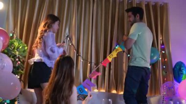 Bir grup arkadaş doğum günü partisi için odayı dekore ediyor, eğleniyorlar.