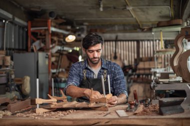 Luthier bir gitar yaratıyor ve geleneksel olarak aletleri kullanıyor. Yapım aşamasında olan bir gitarın gövdesine kelepçe takıyor. Yapıştırıcı yapışkanlığını geliştiriyor.