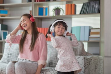 Mutlu Asyalı çocuk annesiyle bir odada eğleniyor ve dans ediyor. Aktif eğlence ve yaşam tarzı kavramı.