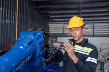 Robotik kol ve işletim makinesinin yanında duran miğfer güvenlikli mühendis. Teknisyen, tamir onarım elektronik işlemleri için kontrol ediyor.