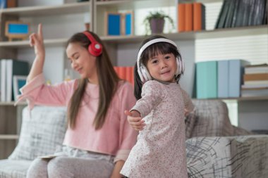 Mutlu Asyalı çocuk annesiyle bir odada eğleniyor ve dans ediyor. Aktif eğlence ve yaşam tarzı kavramı.