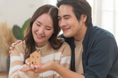 Mutlu Asyalı genç çift yeni ev almak için para biriktirdikleri için model evi tutuyorlar. İş finansmanı, finansal planlama için banka mevduatı.