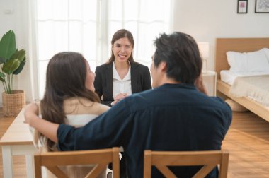 Emlakçı ev anahtarlarını müşteriye veriyor. Asyalı kadın emlakçı ev modeliyle aynı masada otururken alıcıya anahtarları veriyor. Gayrimenkul, yeni mülk alımı, ipotek konsepti