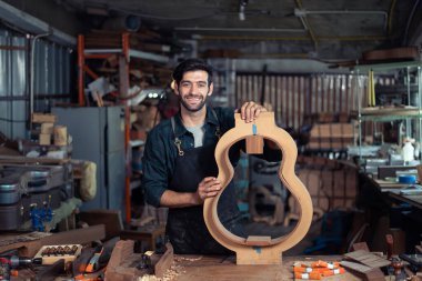 Luthier, el aletleri, sanat ve el sanatları konseptiyle çalışma odasında geleneksel aletleri kullanarak gitarın tepesini yapıyor.