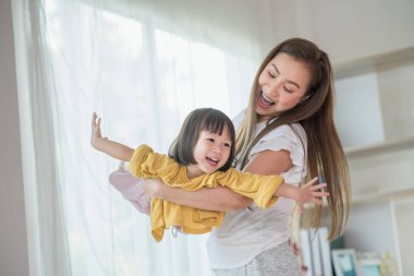 Anne evde kızıyla eğleniyor ve oynuyor, mutlu Asyalı çocuk, aile kavramı