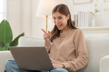 Konsantre olmuş Asyalı kız hafta sonu evde dizüstü bilgisayarda çalışıyor, internette kablosuz internet alışverişi yapmakla meşgul.