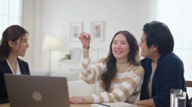 Emlakçı ev anahtarlarını müşteriye veriyor. Asyalı kadın emlakçı ev modeliyle aynı masada otururken alıcıya anahtarları veriyor. Gayrimenkul, yeni mülk alımı, ipotek konsepti