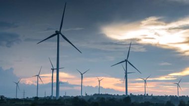 Elektrik üretim istasyonunun zaman aşımı, günbatımında tarım alanlarında rüzgar türbinleri, alternatif enerji yel değirmeni çiftliği, temiz enerji kavramı.