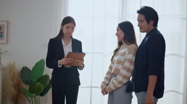 Asyalı finans danışmanı ofisteki genç çifte yeni proje yatırımını açıklıyor. Emlakçı aileyle ipotek seçeneklerini tartışıyor. Finans danışmanıyla ipotek kredisi danışmanlığı.