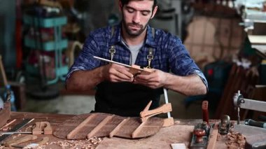 Luthier, el aletleri, sanat ve el sanatları konseptiyle çalışma odasında geleneksel aletleri kullanarak gitarın tepesini yapıyor.