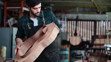 Luthier, el aletleri, sanat ve el sanatları konseptiyle çalışma odasında geleneksel aletleri kullanarak gitarın tepesini yapıyor.