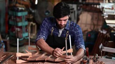 Luthier, el aletleri, sanat ve el sanatları konseptiyle çalışma odasında geleneksel aletleri kullanarak gitarın tepesini yapıyor.