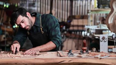 Luthier ahşap müzikal yapıyor ve çalışma odasında el aletleriyle geleneksel aletler kullanıyor.