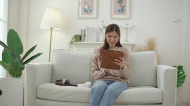 Konsantre olmuş Asyalı kız hafta sonu evde tablet tarama internet üzerinde çalışıyor, genç kadın internet üzerinden bilgisayar sörfü yapmakla meşgul.