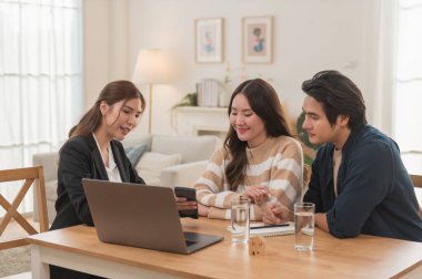 Asyalı finans danışmanı ofisteki genç çifte yeni proje yatırımını açıklıyor. Emlakçı aileyle ipotek seçeneklerini tartışıyor. Finans danışmanıyla ipotek kredisi danışmanlığı.