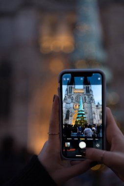 Bordeaux 'daki cam ve çelik Noel ağacının fotoğrafını çeken bir kadın. Telefonu, kişisel bakış açısı, Bordeaux, Fransa