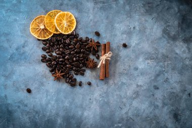 Kahve çekirdekli Noel kompozisyonu, kurutulmuş portakal dilimleri, anason yıldızları ve tarçınlı çubuklar gri dokulu arka planda. Fotokopi alanı ile yukarıdan çekilmiş düz bir kare