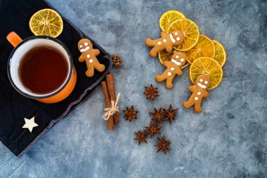 Noel kompozisyonu, zencefilli kurabiye ve gri desenli arka planda bir fincan çay. Yukardan düz atış