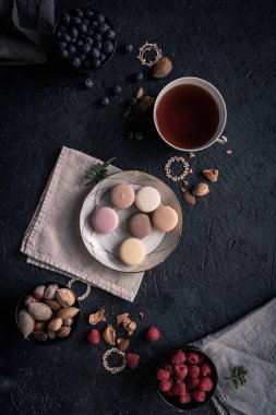 Tabakta badem kurabiyesi olan karanlık ruh hali yemekleri. Kurabiye küçük bir Fransız bademli keki. Yaban mersini, badem, ahududu ve bir fincan çay. metin için boşluk kopyala