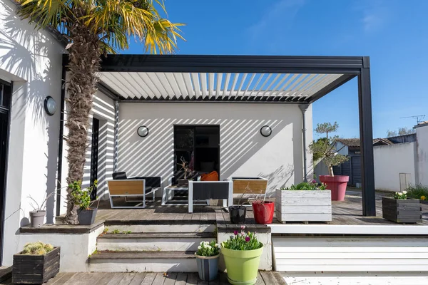 stock image Trendy outdoor patio pergola shade structure, awning and patio roof, garden lounge, chairs, metal grill surrounded by landscaping