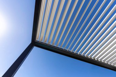 Moda olan açık hava biyo-limatik pergola. Metal yapının içinde berrak gökyüzü parlıyor.