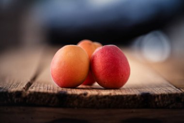 Ahşap şarap masasında üç taze kayısı. Yakın çekim.