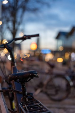 Arka planda bulanık şehir ışığı olan bir bisiklet eyerinin yakın çekimi