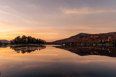 Renkli bir sonbahar akşamı göle yansıyor. Dağ gölünde renkli sonbahar günbatımı. Renkli sonbahar manzarası. Parc national Mont Tremblant. Quebec 'te. Kanada 'da sonbahar