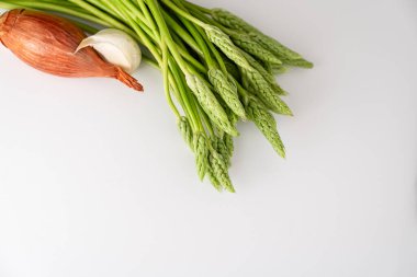 Beyaz arka planda pişmeye hazır taze kuşkonmaz, soğan ve sarımsak. metin için boşluk kopyala. en üstteki görüntü