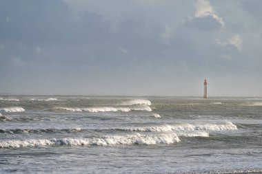 Fırtınada mavi gökyüzünde dalgalar olan deniz feneri.