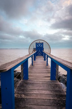 Fransa 'nın Aytre kentindeki Atlantik kıyısındaki geleneksel balıkçı kulübesine açılan mavi kapılı tahta köprü.