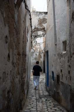 Eski Medine, Tunus ve Tunus 'ta dar bir sokakta yürüyen bir adam. Arkadan ateş ediyorlar..