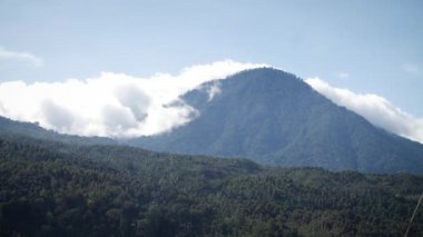 Sabahları arkasında beyaz bulutlar olan güzel bir dağ. Bali, Endonezya. Yüksek kaliteli FullHD yavaş çekim görüntüleri.