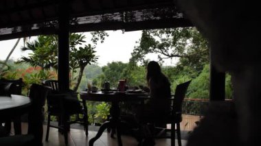 Restoran otelinde kahvaltı ederken telefonuna bakan bir kadın. Bali, Endonezya. Yüksek kaliteli FullHD yavaş çekim görüntüleri.