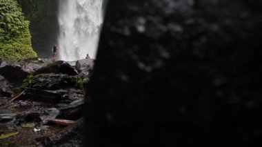 Ormanın ortasında, Nungnung Şelalesi 'nin önündeki kadın. Bali, Endonezya. Yüksek kaliteli FullHD yavaş çekim görüntüleri.