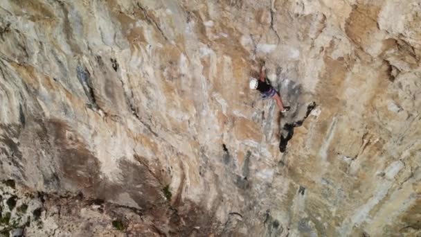 ギリシャのカリムノス島の急な壁で難しいスポーツ登山ルートを登る強い女性のクライマーの空中ドローンビュー 高品質の4K映像 — ストック動画
