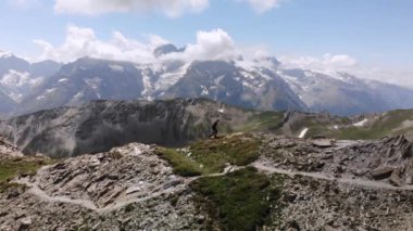 Arkasında la Meije zirvesi olan genç bir kadının Alplerde yürüdüğü 4K Drone görüntüleri. Yüksek kalite 4k görüntü