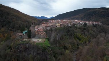 Castellfollit de la Roca katalan kasabasında küçük evler, uçurumlar ve Katalonya, İspanya 'daki San Salvador kilisesi. Yüksek kalite 4k drone görüntüsü