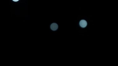 Düşen beyaz noktalar siyah arka plana odaklanmış. Küçük daireler çizerek canlandırılmış element monokrom soyut 4K video hareketi izole ediliyor.