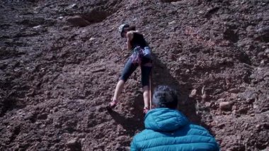 Arkadaşlar doğada kırmızı kayalara tırmanıyor. Yüksek kalite 4k görüntü